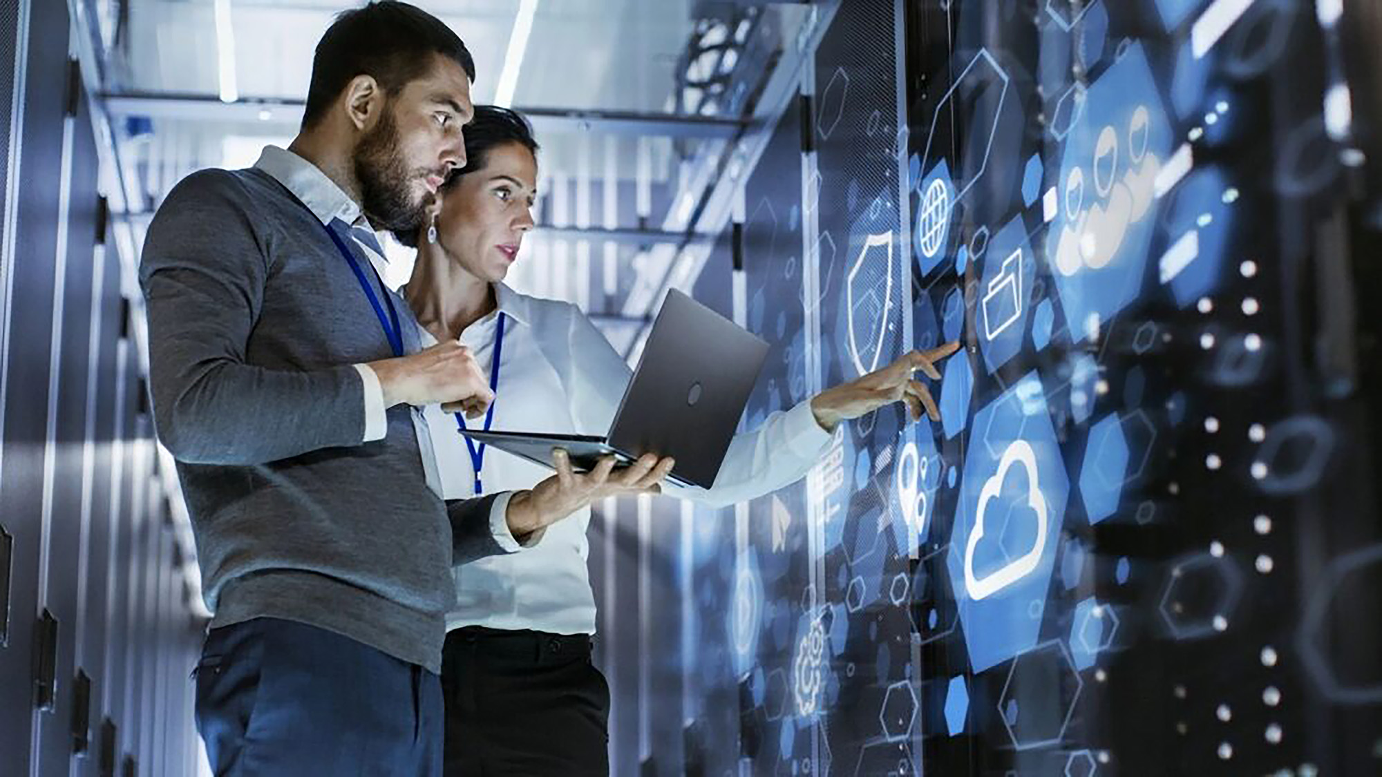 Two professionals examining a digital screen featuring an AUDDIS report with a Payer Reference Not Unique reason code in a server room.