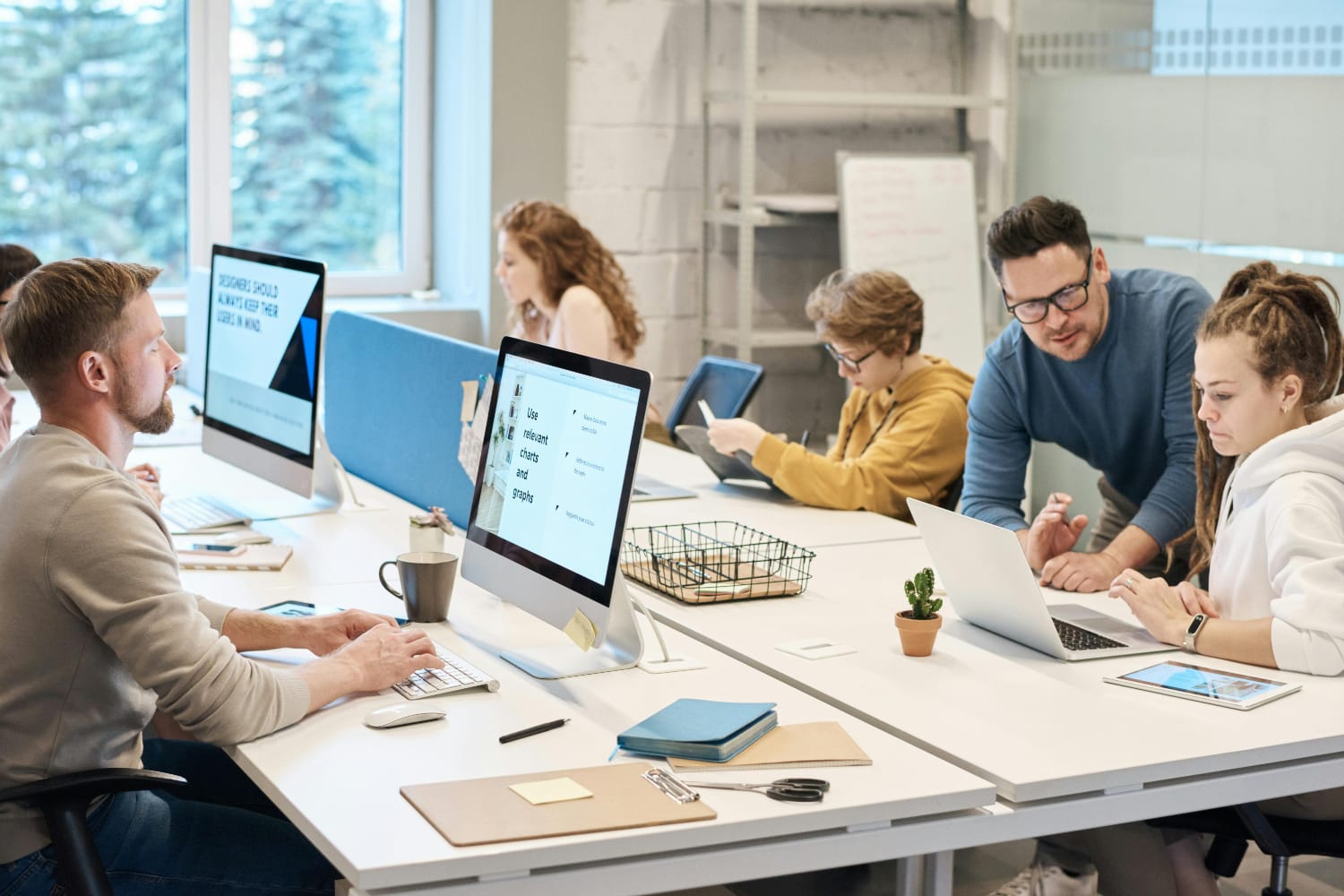 A group of individuals collaborating in a modern office environment with computers and devices.