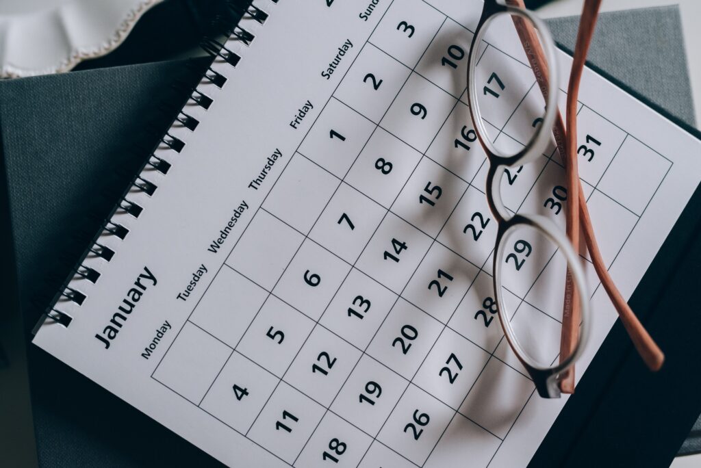 Spiral-bound calendar for January with a pair of glasses resting on top.