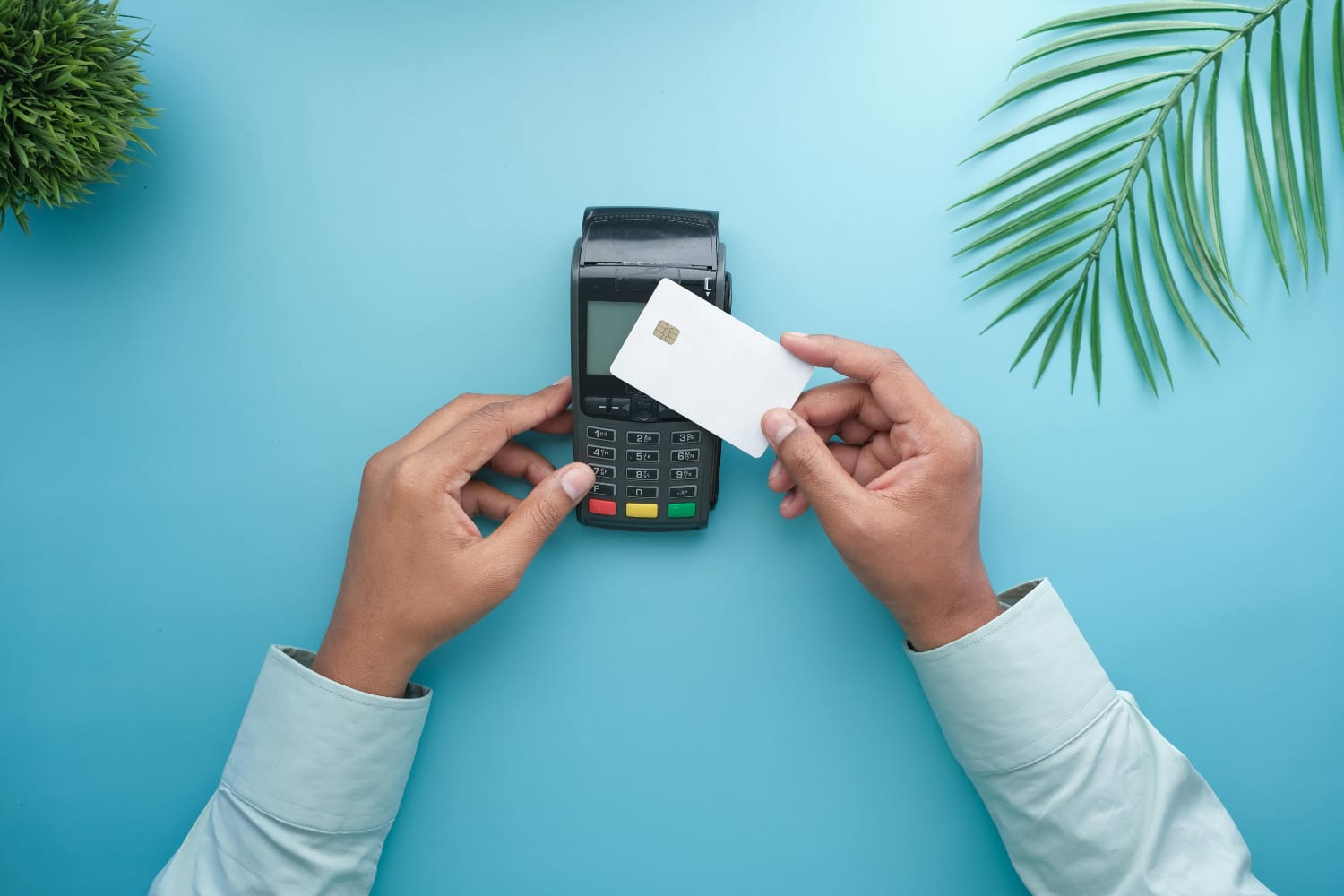 Person holding a blank card above a payment terminal on a blue background.