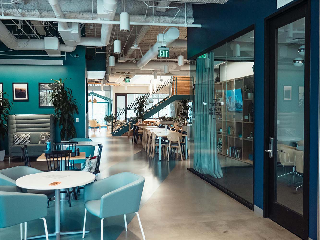 Interior view of a modern office featuring seating areas and plants in a well-lit space.